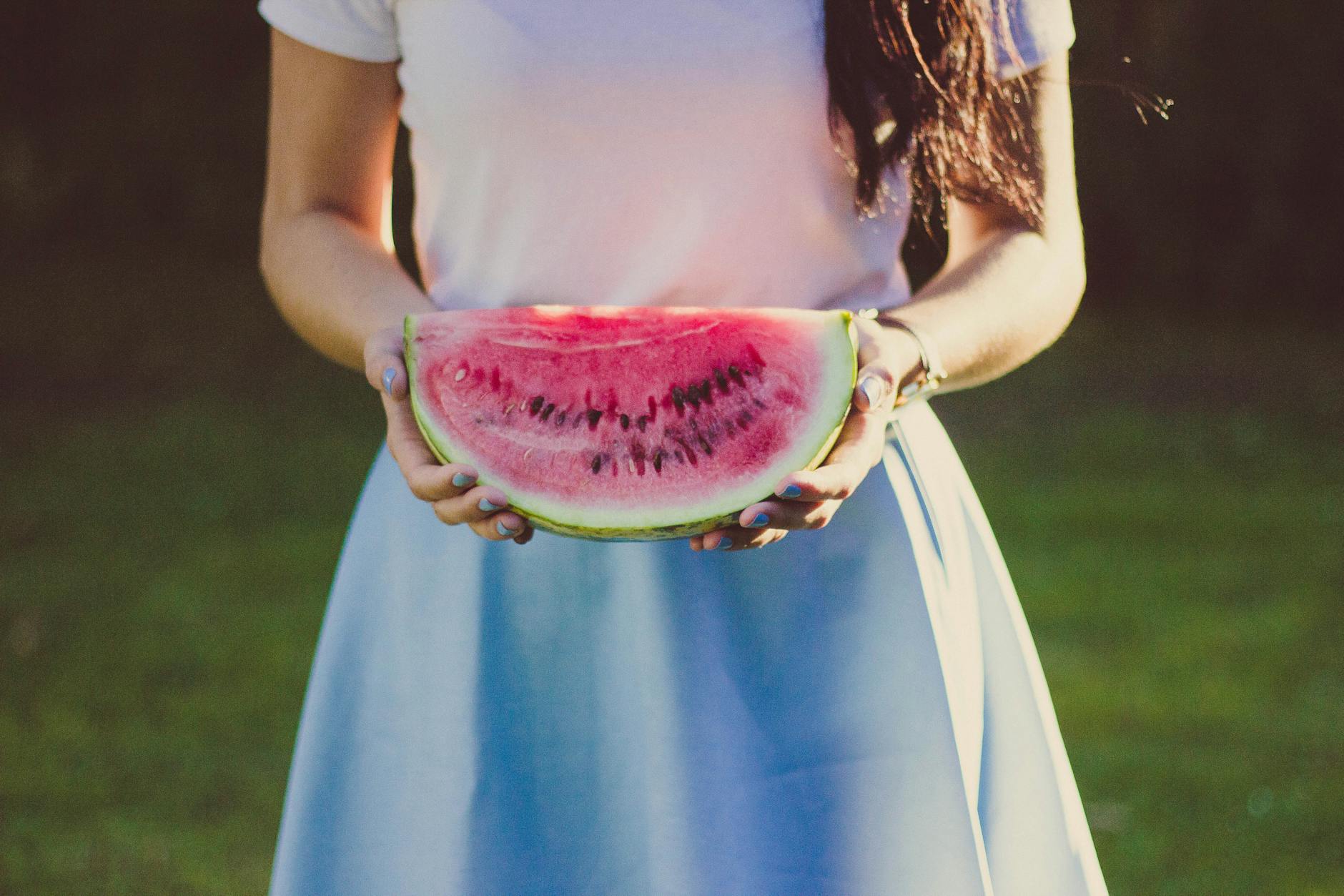 woman in white and blue dress holding water melon