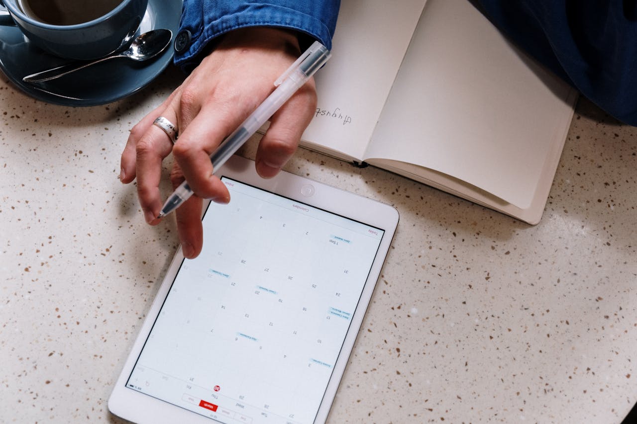 Person reviewing a digital planner on a tablet, focusing on organizing their tasks.