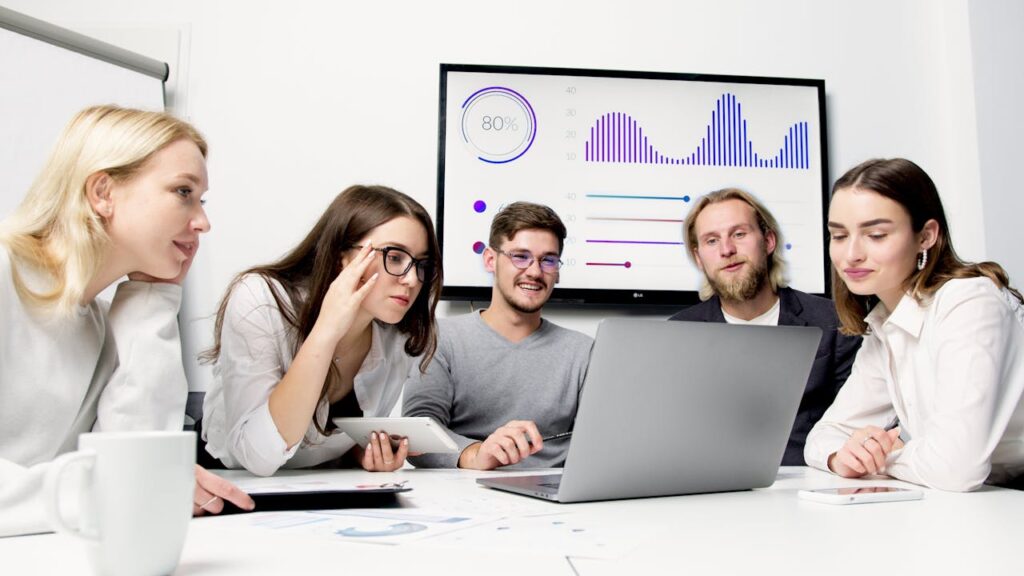 Group of people collaborating around a laptop, focused on selling digital products.