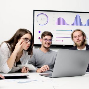 Group of people collaborating around a laptop, focused on selling digital products.