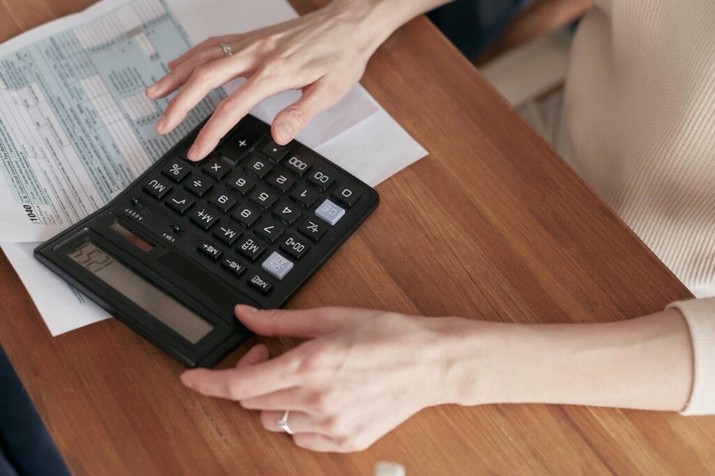 Person holding a calculator, symbolizing the cost-saving benefits of selling digital products without physical inventory.