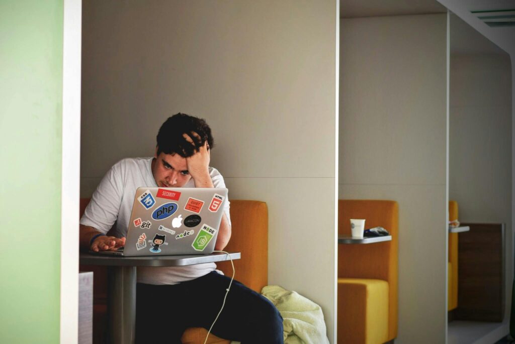 A man showing stress and frustration while working remotely on a laptop, struggling to earn as an affiliate.